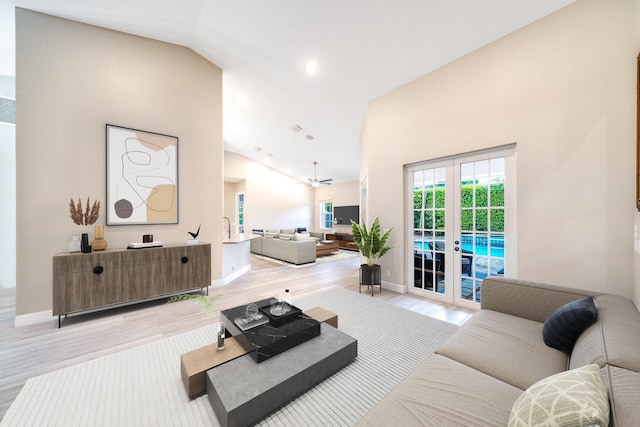 living room featuring ceiling fan, light hardwood / wood-style floors, high vaulted ceiling, and french doors