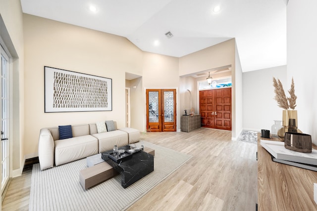 living room with french doors, high vaulted ceiling, and light hardwood / wood-style flooring