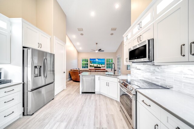 kitchen with kitchen peninsula, stainless steel appliances, white cabinetry, and sink