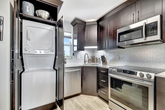 kitchen featuring backsplash, appliances with stainless steel finishes, light hardwood / wood-style floors, sink, and dark brown cabinets