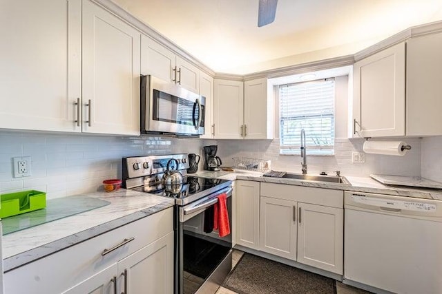 kitchen featuring backsplash, sink, appliances with stainless steel finishes, light stone counters, and white cabinetry