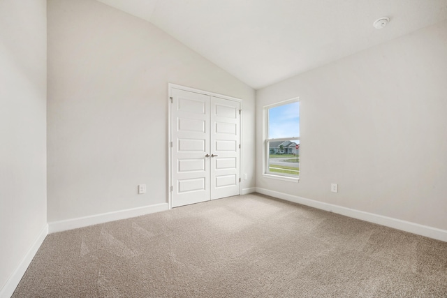 unfurnished bedroom featuring carpet, a closet, and lofted ceiling