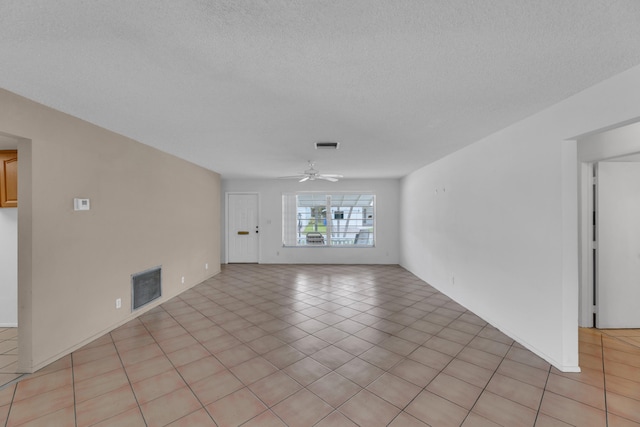 tiled empty room with ceiling fan and a textured ceiling