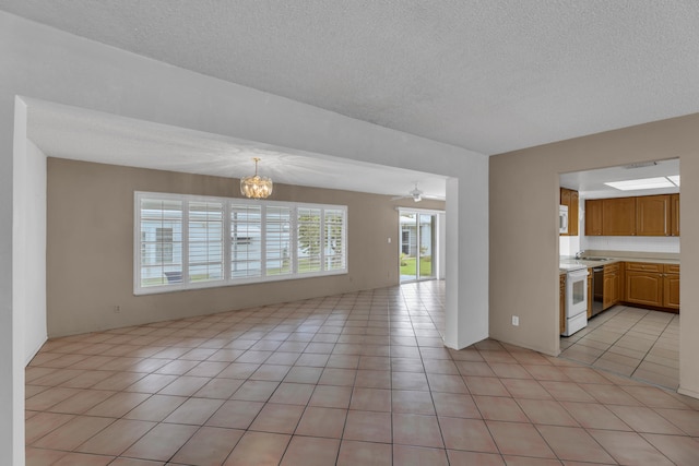 interior space with a textured ceiling, ceiling fan with notable chandelier, sink, and light tile patterned floors