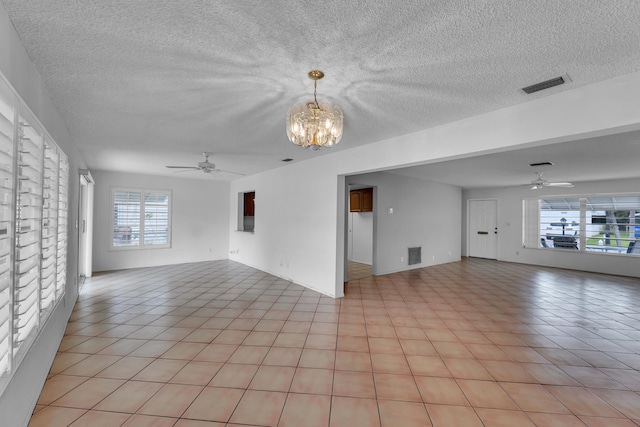 empty room featuring a textured ceiling, ceiling fan with notable chandelier, and light tile patterned floors