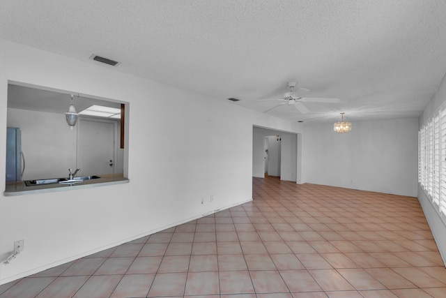 spare room featuring a textured ceiling, ceiling fan with notable chandelier, sink, and light tile patterned floors