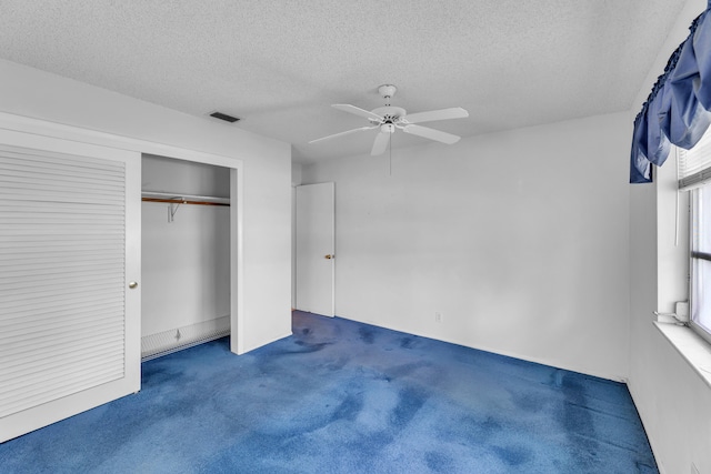 unfurnished bedroom featuring a textured ceiling, dark colored carpet, ceiling fan, and a closet