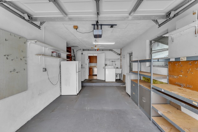 garage with a garage door opener, washer / dryer, white refrigerator, and sink