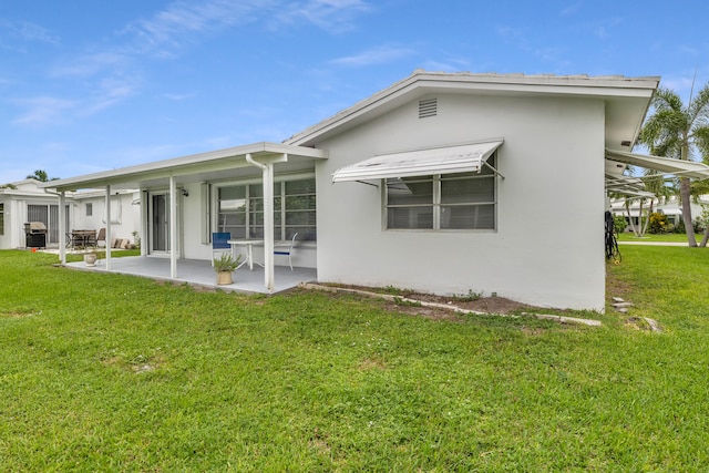 rear view of property featuring a patio and a yard