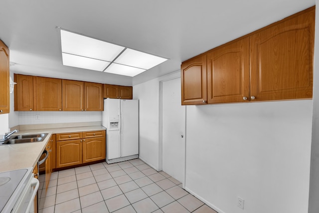 kitchen featuring backsplash, white appliances, light tile patterned flooring, and sink