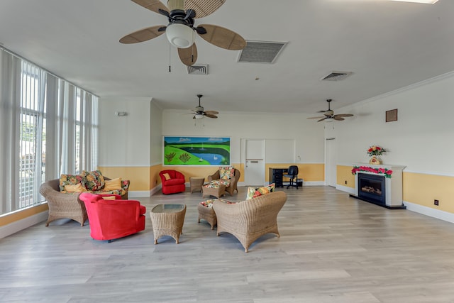 living room with light wood-type flooring, ceiling fan, and crown molding