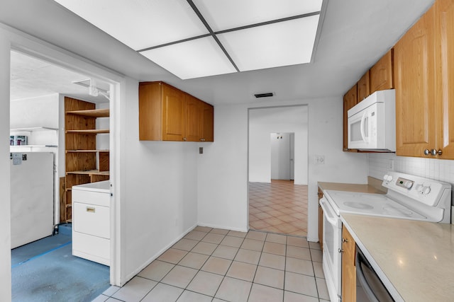 kitchen with washer / clothes dryer, light tile patterned flooring, white appliances, and decorative backsplash