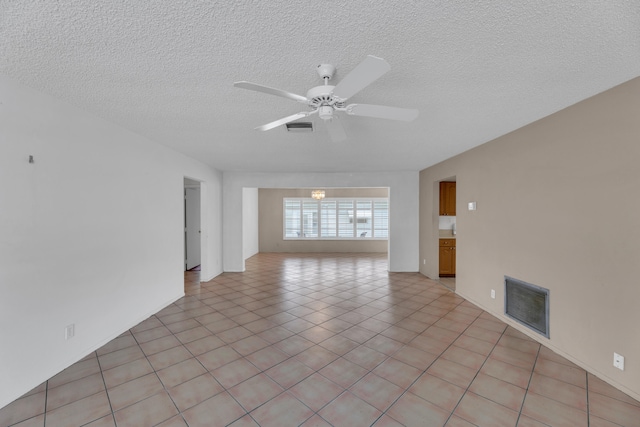 empty room with ceiling fan, a textured ceiling, and light tile patterned floors