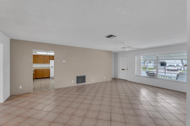 interior space featuring ceiling fan, light tile patterned flooring, and a textured ceiling