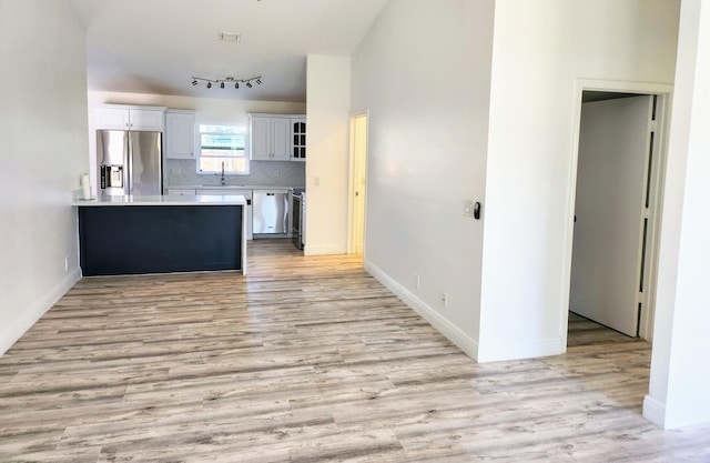 kitchen featuring light hardwood / wood-style floors, decorative backsplash, sink, stainless steel fridge with ice dispenser, and white cabinetry