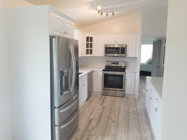 kitchen featuring backsplash, white cabinetry, appliances with stainless steel finishes, lofted ceiling, and light hardwood / wood-style flooring