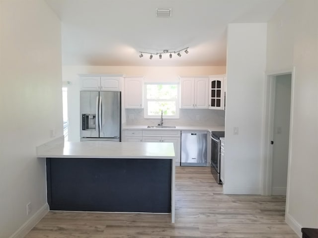 kitchen featuring white cabinetry, appliances with stainless steel finishes, sink, kitchen peninsula, and light hardwood / wood-style flooring