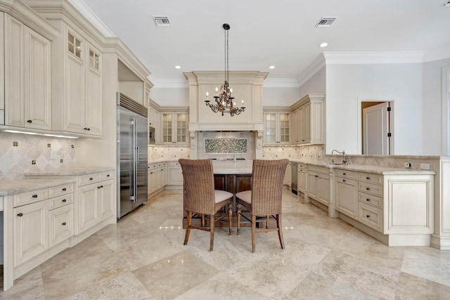 kitchen with a chandelier, stainless steel appliances, cream cabinetry, and visible vents