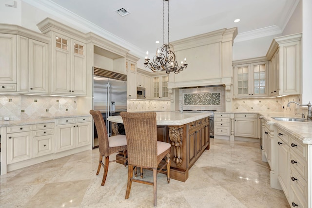 kitchen featuring built in appliances, backsplash, light tile patterned floors, sink, and a center island with sink