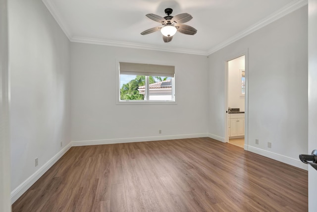 empty room with a ceiling fan, ornamental molding, baseboards, and wood finished floors
