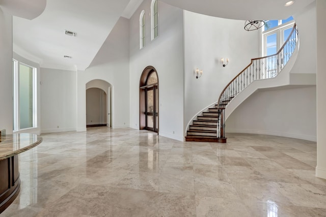 entryway featuring a high ceiling, visible vents, arched walkways, marble finish floor, and stairs
