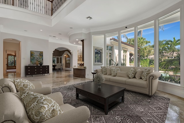 tiled living room with a towering ceiling, crown molding, and a healthy amount of sunlight