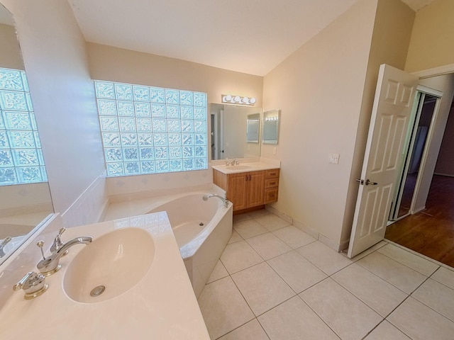 bathroom with vaulted ceiling, a bathtub, double vanity, and wood-type flooring