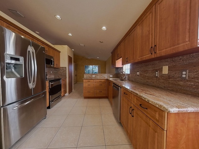 kitchen featuring stainless steel appliances, tasteful backsplash, light stone countertops, lofted ceiling, and kitchen peninsula