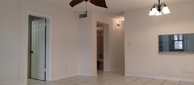 spare room featuring light tile patterned flooring and ceiling fan with notable chandelier