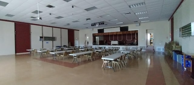 interior space featuring a paneled ceiling, a kitchen bar, and a towering ceiling