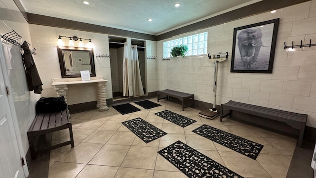 bathroom with a shower with shower curtain, ornamental molding, tile patterned flooring, a textured ceiling, and tile walls