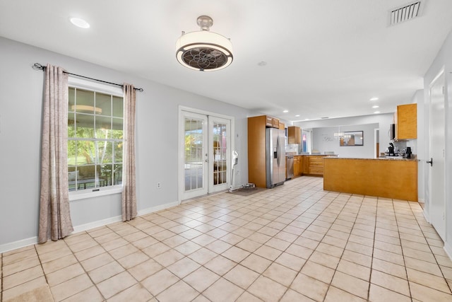 kitchen with kitchen peninsula, light tile patterned floors, french doors, and stainless steel refrigerator with ice dispenser