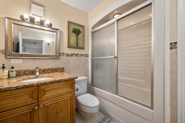 full bathroom with enclosed tub / shower combo, toilet, vanity, tile walls, and tile patterned floors