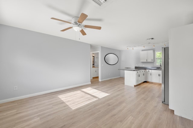 unfurnished living room featuring light hardwood / wood-style flooring, ceiling fan, and track lighting