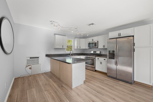 kitchen with appliances with stainless steel finishes, light hardwood / wood-style floors, sink, white cabinets, and track lighting