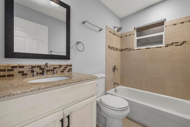 full bathroom featuring tiled shower / bath combo, toilet, decorative backsplash, and vanity