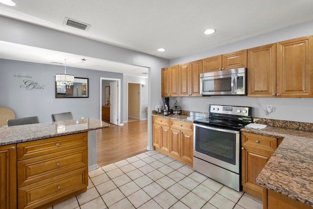 kitchen featuring light tile patterned floors, pendant lighting, and stainless steel appliances