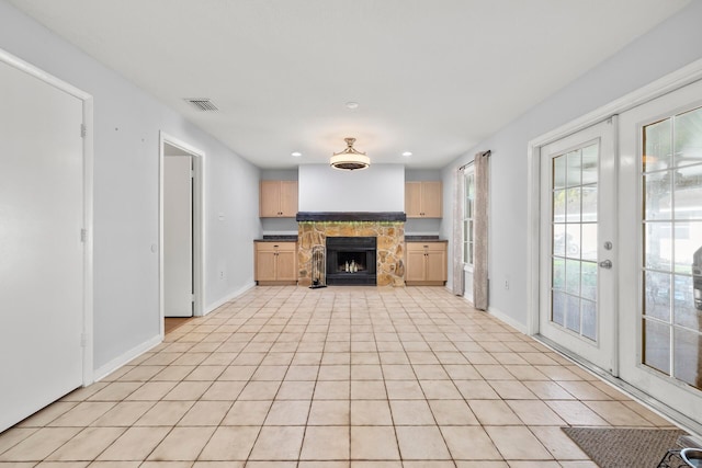 unfurnished living room with a fireplace, light tile patterned floors, and french doors