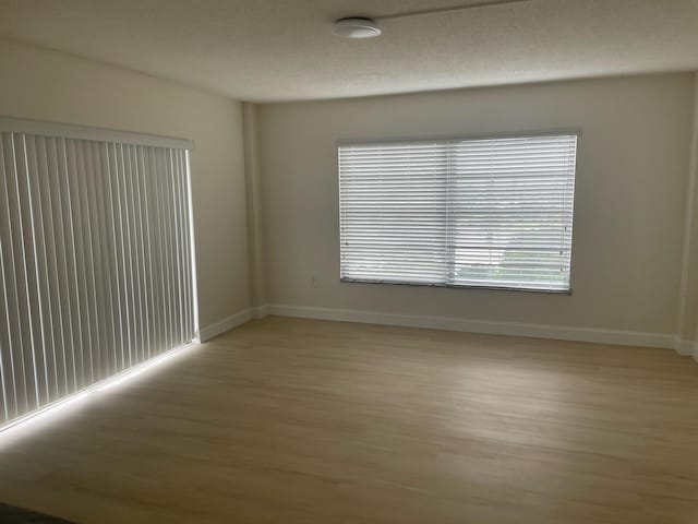 empty room featuring light wood-type flooring and a textured ceiling