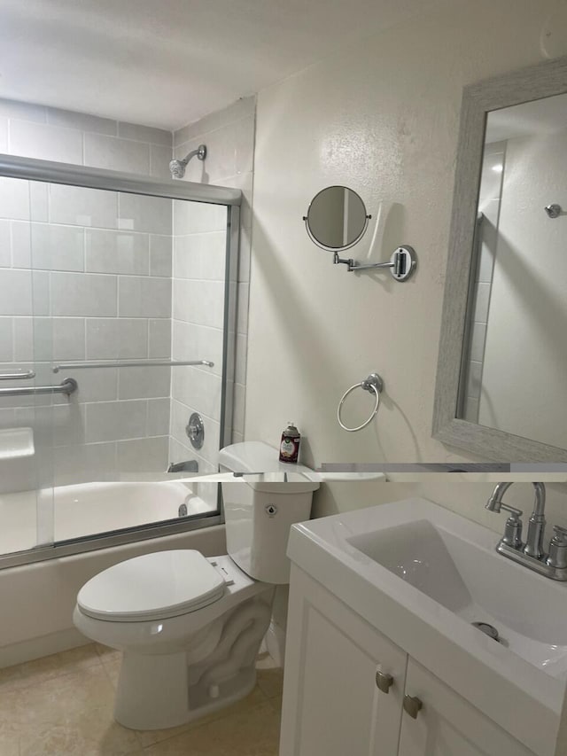 full bathroom with combined bath / shower with glass door, toilet, tile patterned flooring, and vanity