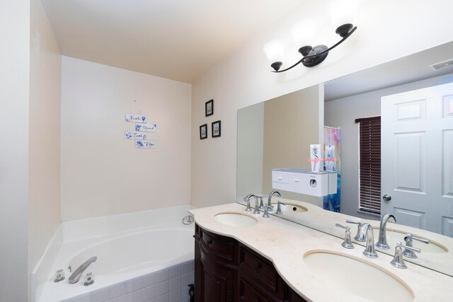 bathroom featuring a relaxing tiled tub and vanity