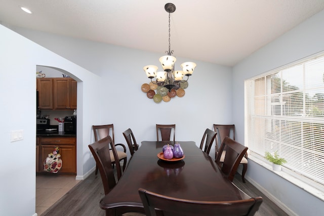 dining area featuring a notable chandelier, vaulted ceiling, and hardwood / wood-style floors