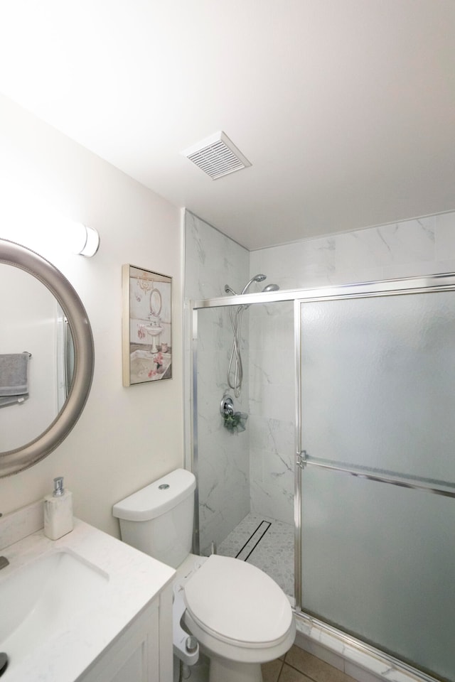 bathroom featuring tile patterned flooring, a shower with shower door, vanity, and toilet