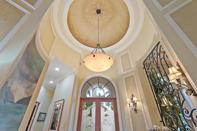 interior space featuring a towering ceiling, ornamental molding, and french doors