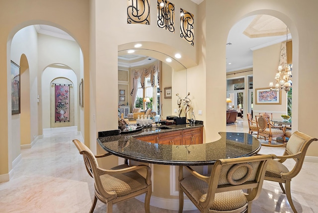 interior space featuring a high ceiling, a notable chandelier, light tile patterned flooring, and ornamental molding