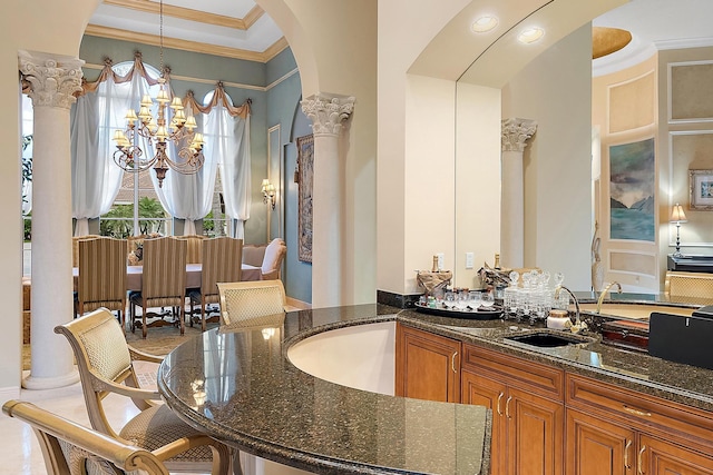 interior space with an inviting chandelier, crown molding, vanity, and ornate columns