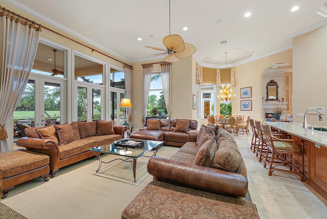 living room featuring ceiling fan with notable chandelier, sink, ornamental molding, and a healthy amount of sunlight