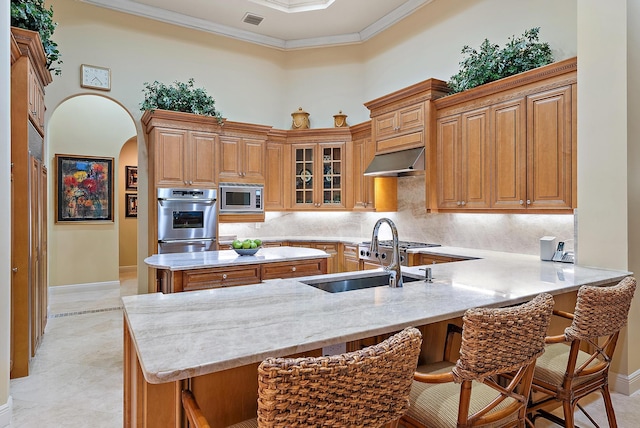 kitchen featuring a kitchen breakfast bar, backsplash, crown molding, and stainless steel appliances