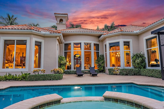 back house at dusk with a patio area