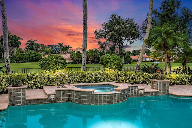 pool at dusk with an in ground hot tub